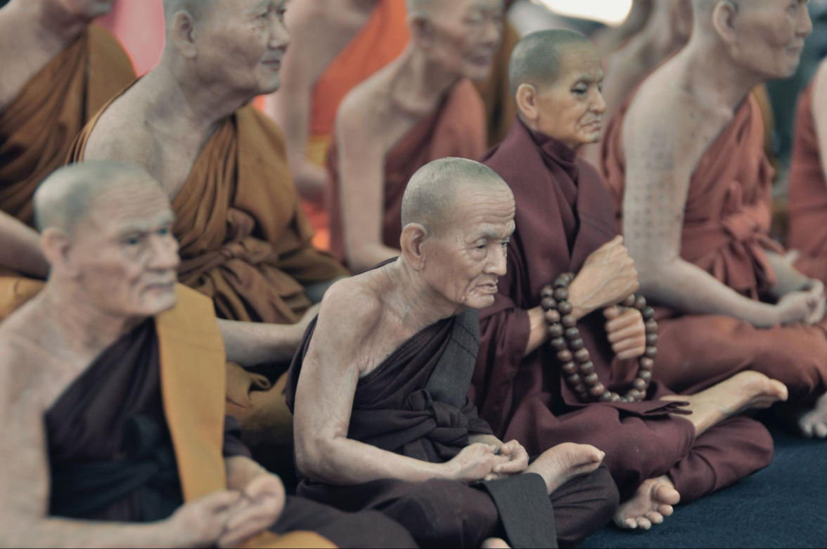 Older monks performing rituals inside a monastery.