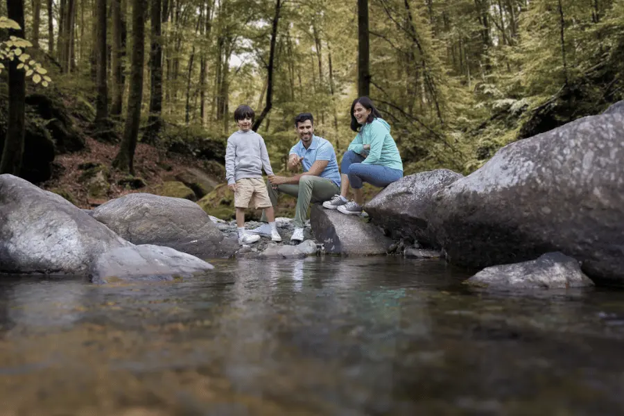 Parents and child enjoying a peaceful riverside moment near Rakkh Resort in Himachal