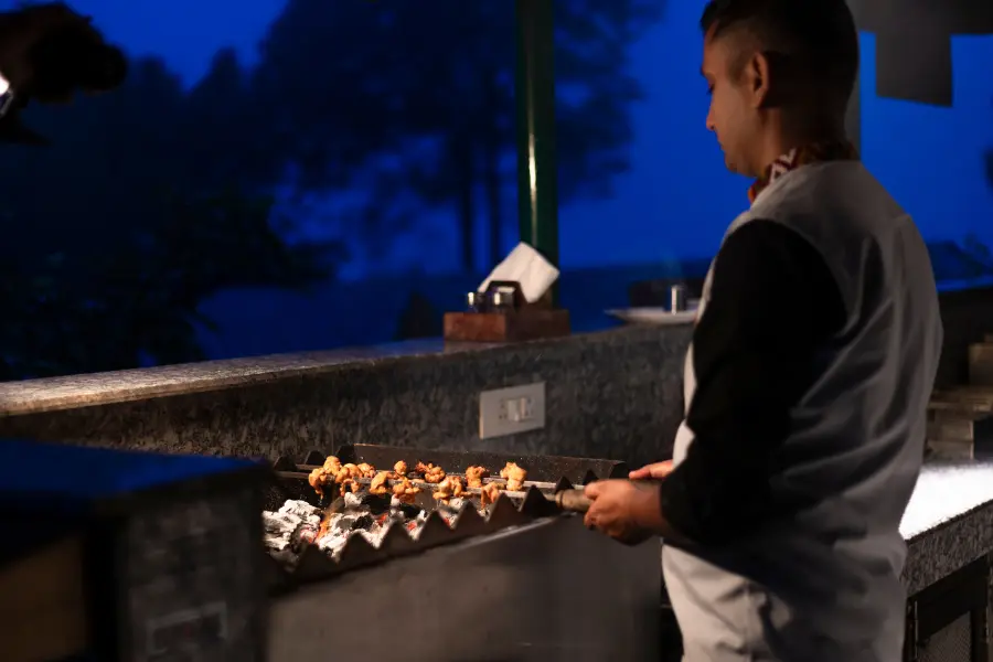 A view of chef grilling kebabs at Rakkh Resort’s outdoor barbecue under the evening sky.
