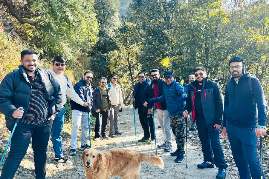 A view of corporate group trekking through the scenic forest trails with a dog at Rakkh Resort.