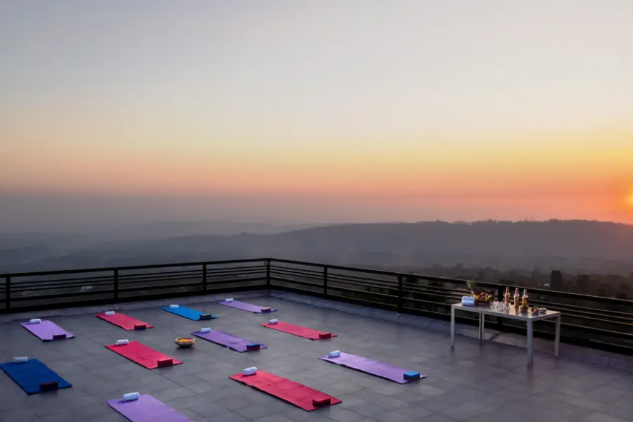 A view of yoga mats arranged on a terrace at sunrise, overlooking the serene hills at Rakkh Resort.