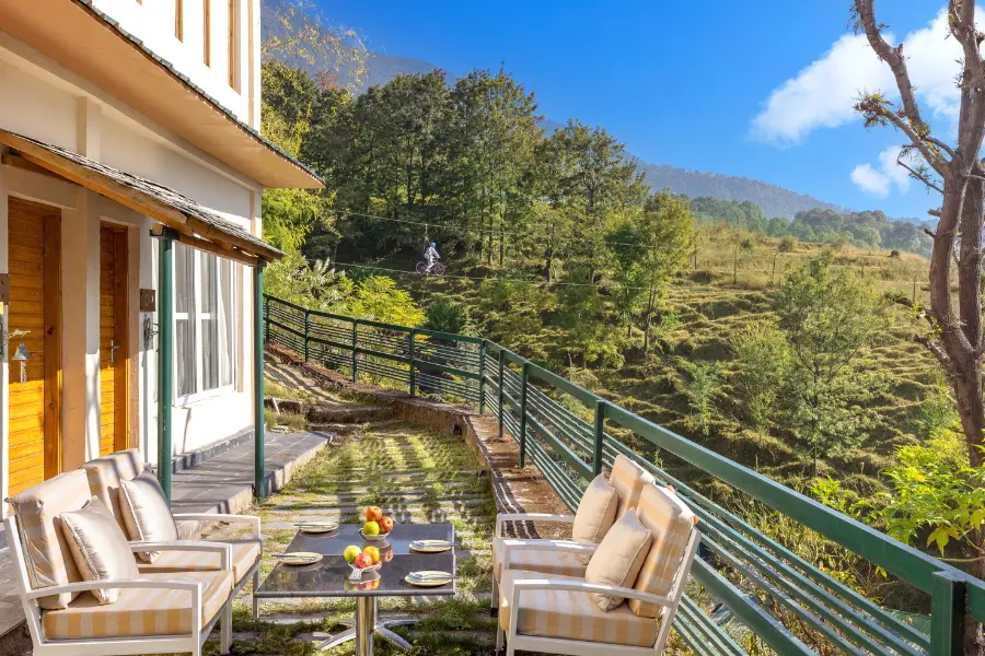 View of balcony seating overlooking green hills and mountains.