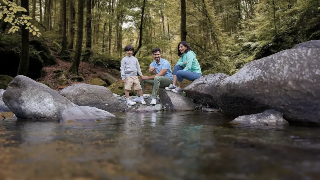 Parents and child enjoying a peaceful riverside moment near Rakkh Resort in Himachal